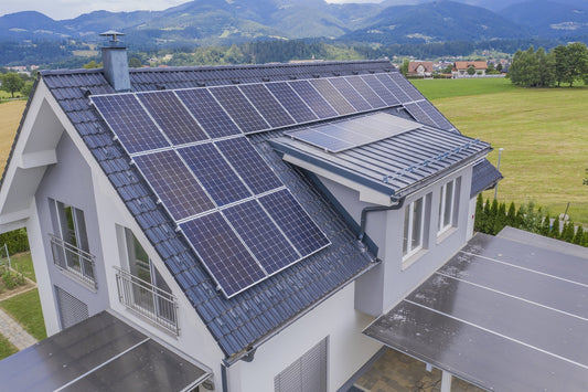 Una casa singola moderna dai colori bianco e grigio, un tetto spiovente coperto quasi interamente da pannelli fotovoltaici.